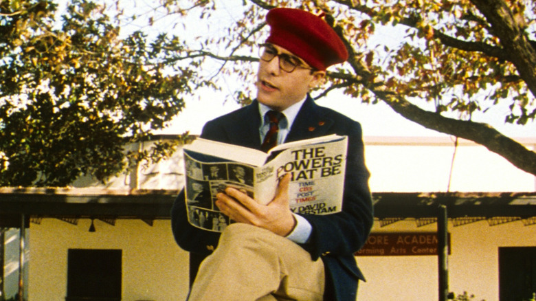 Student Max Fischer sitting outside on his high school campus reading "The Powers that Be"