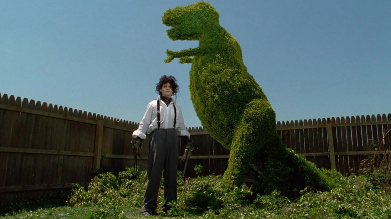 Edward stands next to a T-rex topiary in "Edward Scissorhands" (1990)