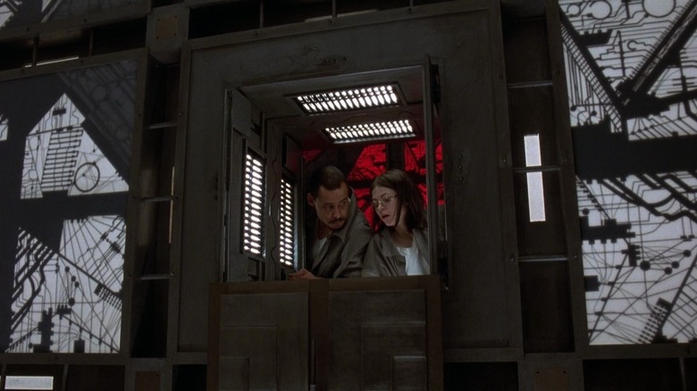 Quentin and Joan in Cube looking from a red room into a white one