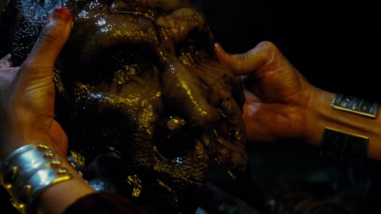 Someone holding a grotesque, humanoid, wet face mask, in Mimic