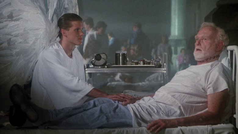 An angel sitting at the bedside of Father Tom Kanavan, who has stitches on his neck as though his head's been reattached, in The Exorcist III