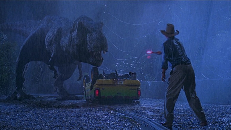 Grant holds a flare facing a T-rex and an overturned car in "Jurassic Park" (1993)