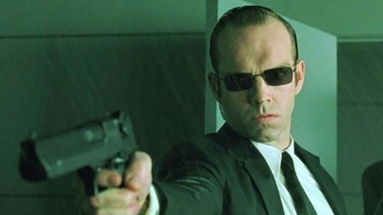 Agent Smith pointing a handgun in the rain in "The Matrix"
