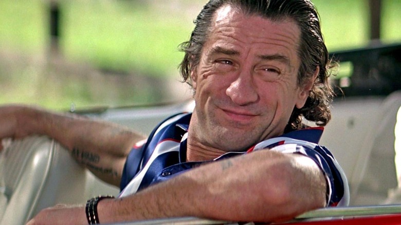 Max Cady smiling to the side while sitting in the driver seat of a convertible in "Cape Fear"