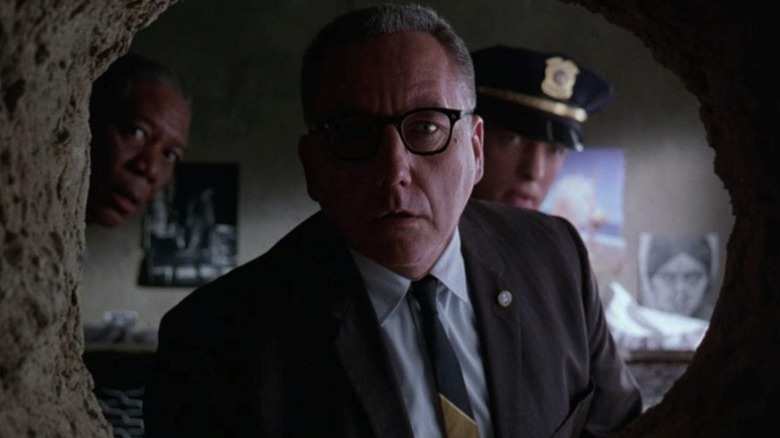Warden Samuel Norton staring through a hole in a jail cell in "The Shawshank Redemption"