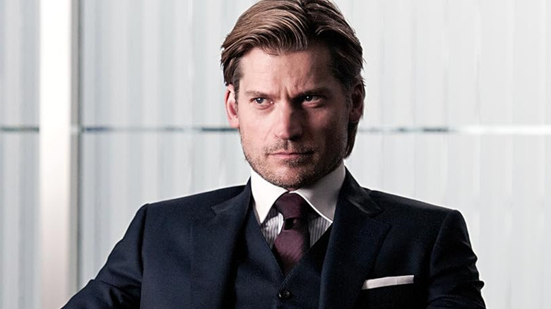 Clas Greve stares while wearing a dapper suit with maroon tie in 