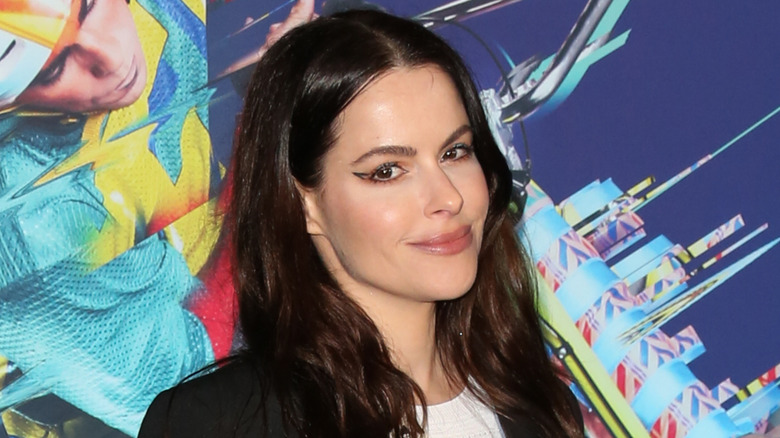 Emily Hampshire with a jacket and shoulder strap