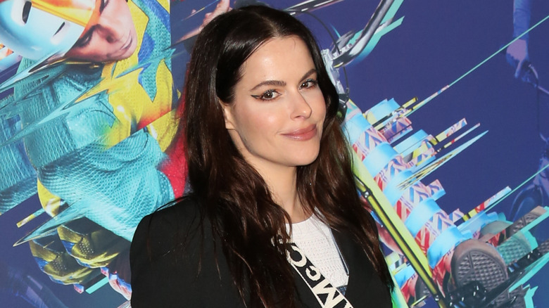 Emily Hampshire with a jacket and shoulder strap