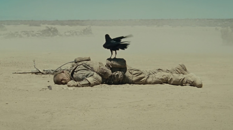 Matthews lying on the ground with a crow on his back in The Wall