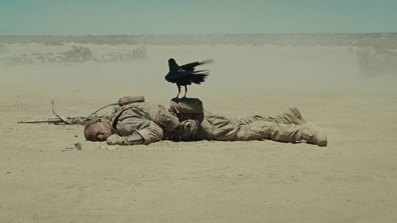Matthews lying on the ground with a crow on his back in The Wall
