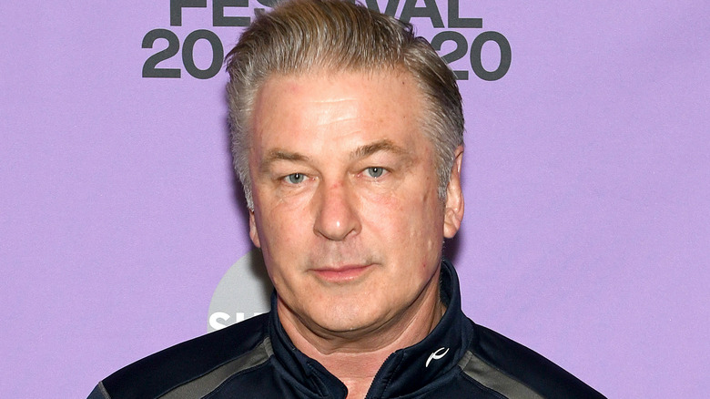 Alec Baldwin standing in front of purple backdrop