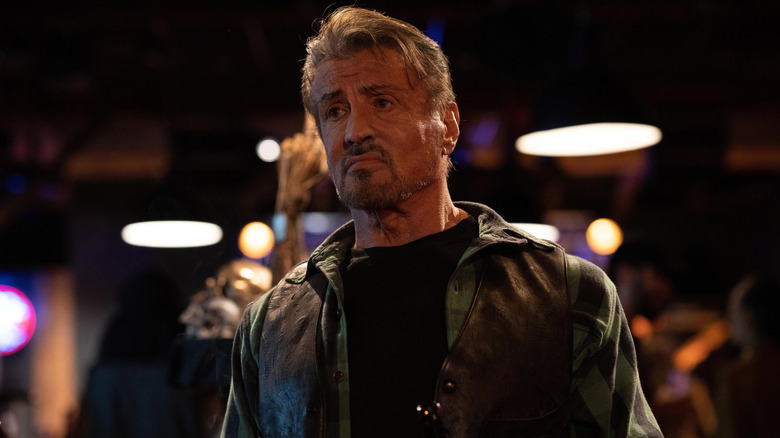 Barney Ross stands in a bar with a scowl on his face in "The Expendables 4" (2023)