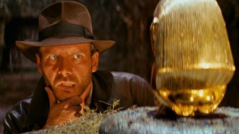 Indiana Jones examining a golden statue in Raiders of the Lost Ark (1981)