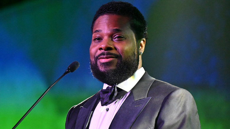 Malcolm-Jamal Warner standing at a microphone