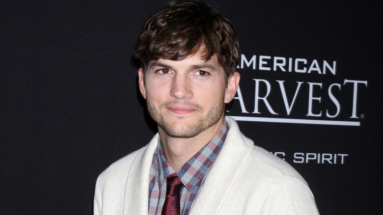 Ashton Kutcher smiling in flannel and tie