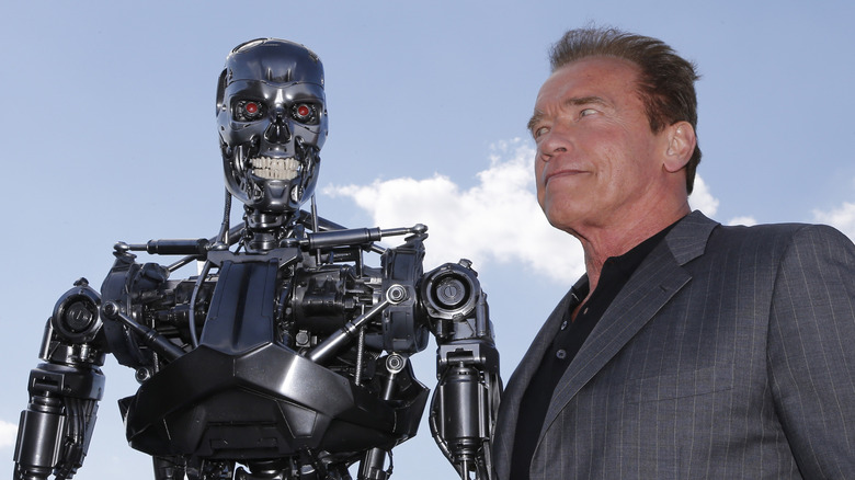 Arnold Schwarzenegger stands next to a Terminator exoskeleton