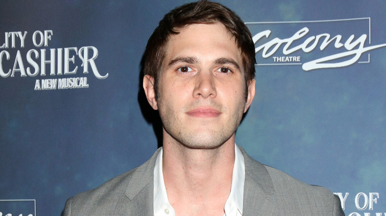 Blake Jenner posing at an event in a gray coat