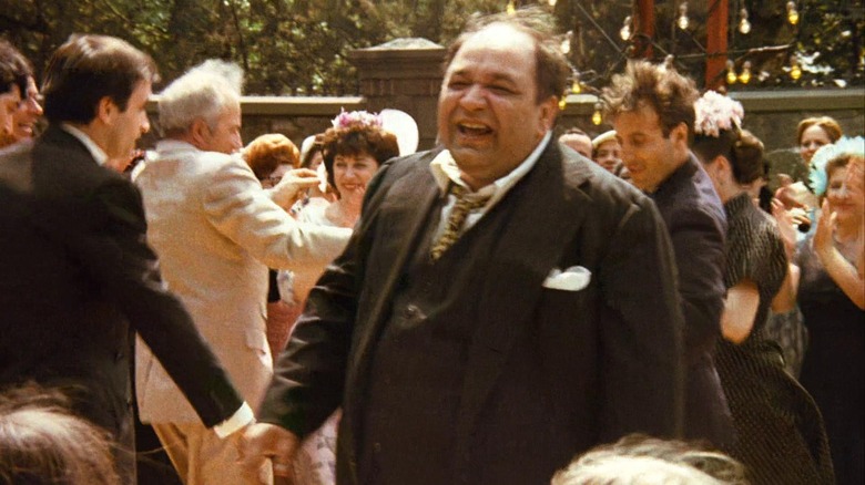 Clemenza at a wedding, laughing among the crowd.