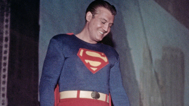 George Reeves dressed as Superman in front of a fake city backdrop