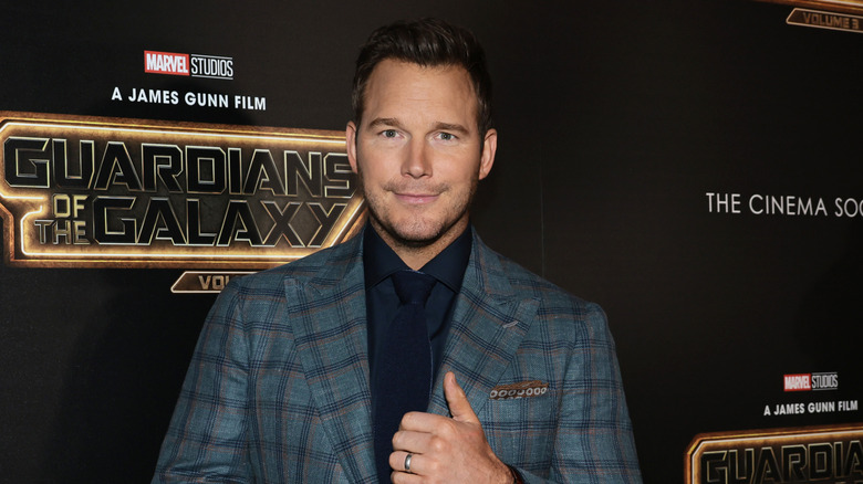Chris Pratt in a suit in front of a "Guardians of the Galaxy" wall