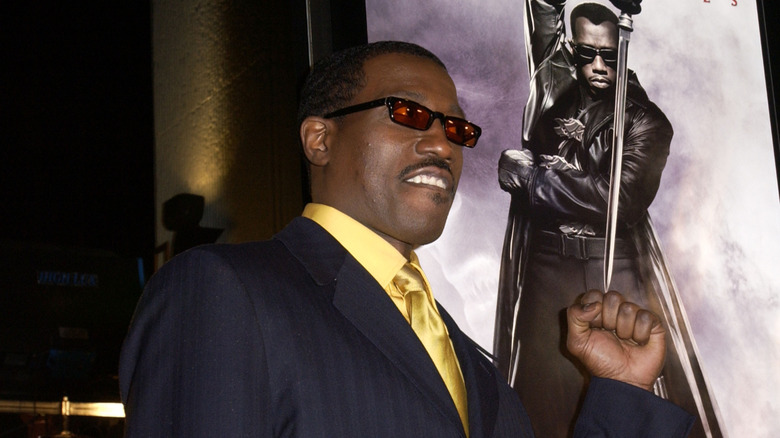 Wesley Snipes holds up his fist in front of a "Blade" poster