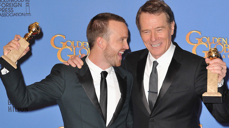 aaron paul and bryan cranston smiling holding awards