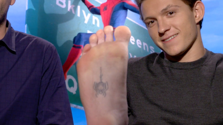 Tom Holland holding up foot