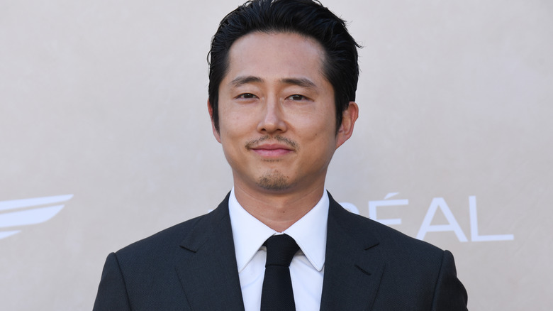 Steven Yeun smiling in suit