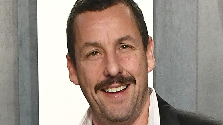 Adam Sandler speaking into a microphone