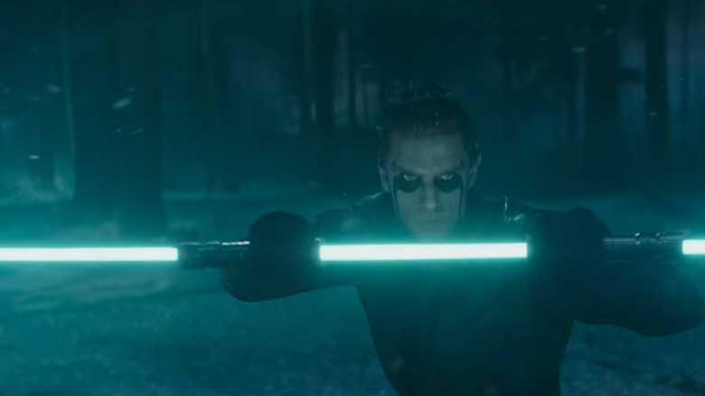 A strange man holds a double-bladed blue lightsaber in the snow at night in Ahsoka season 2 (2027