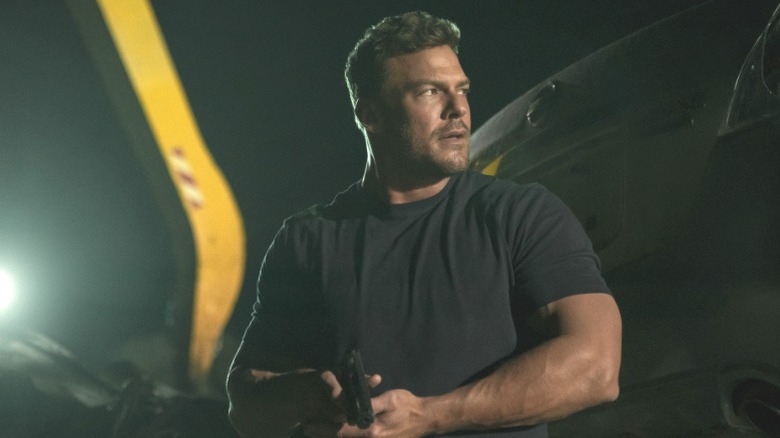 Reacher draws his gun on a night mission in "Reacher" (2022-present)