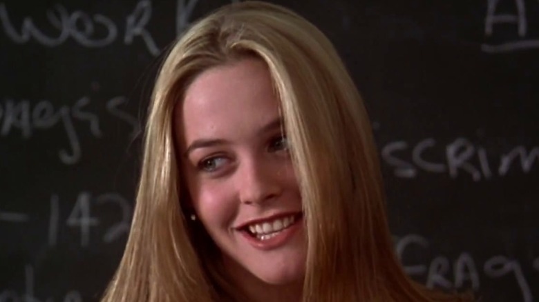 Alicia Silverstone in Clueless smiling against blackboard