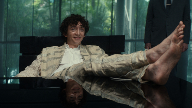 Kavalier smiling and sitting at a desk with barefoot feet up
