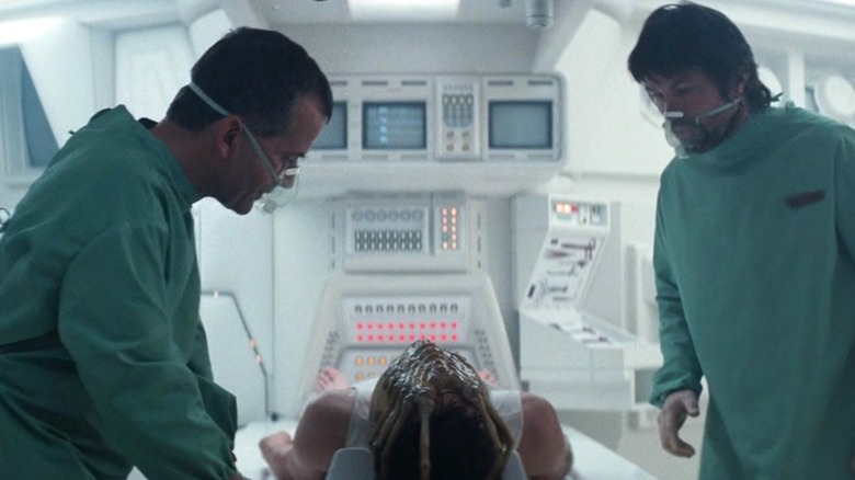 Ash and Dallas stand next to Kane on a table