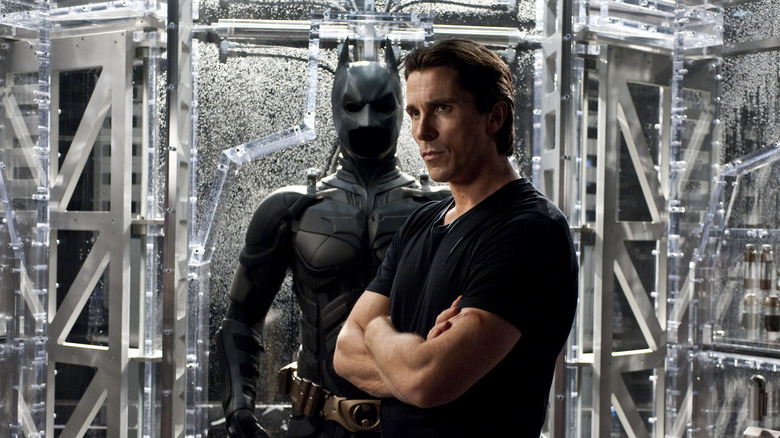Bruce Wayne standing in front of his Batsuit in The Dark Knight Rises (2012)