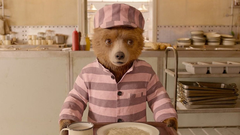 Paddington in his prison uniform holding a tray and looking confused in Paddington 2