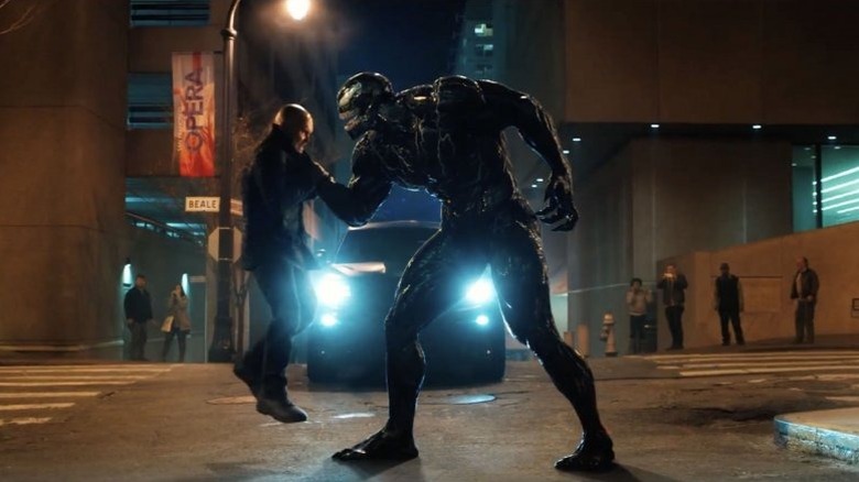 Venom lifting a man up in the middle of a street on Venom