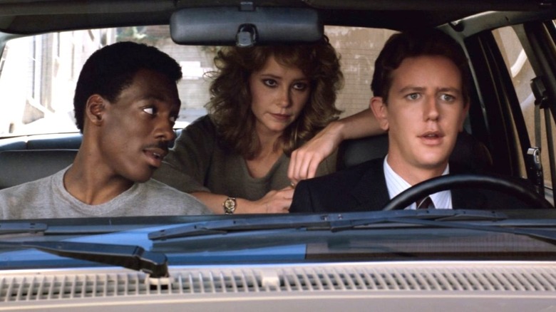 Axel Foley, Jenny Summers, and Billy Rosewood sit in a car in Beverly Hills Cop (1984)