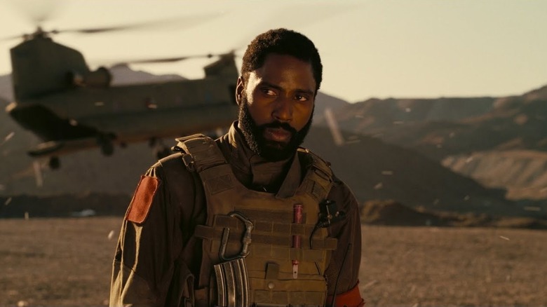 A helicopter taking off from a landing zone behind the Protagonist in Tenet (2020)