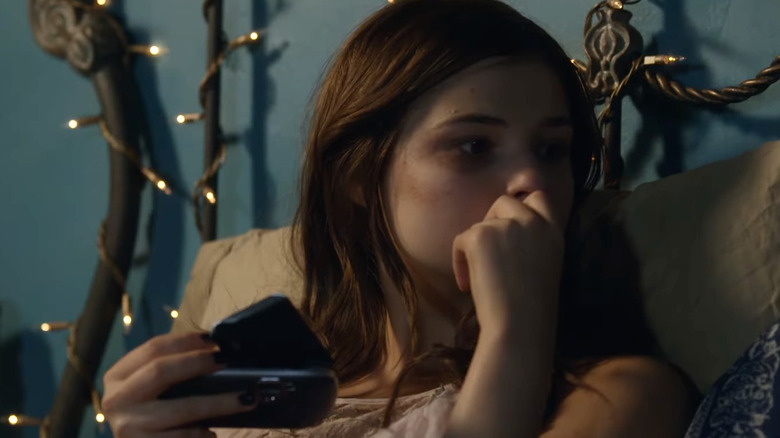 Holding a pager, Quinn Brenner looks pensive in Insidious: Chapter 3