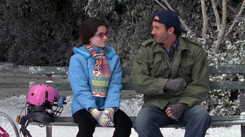 April and Luke sitting on a bench in the snow talking to each other in Gilmore Girls