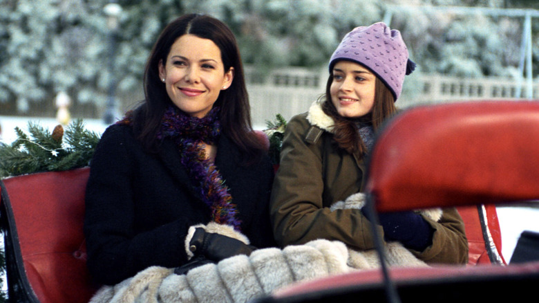 Rory and Lorelai smiling and riding in a horse drawn carriage on Gilmore Girls