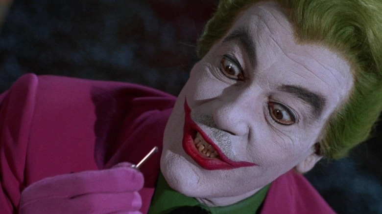 The Joker inspecting a tiny item with fury in "Batman"