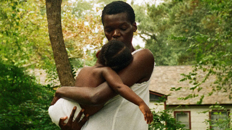 Evelyn holds a child in her arms outside