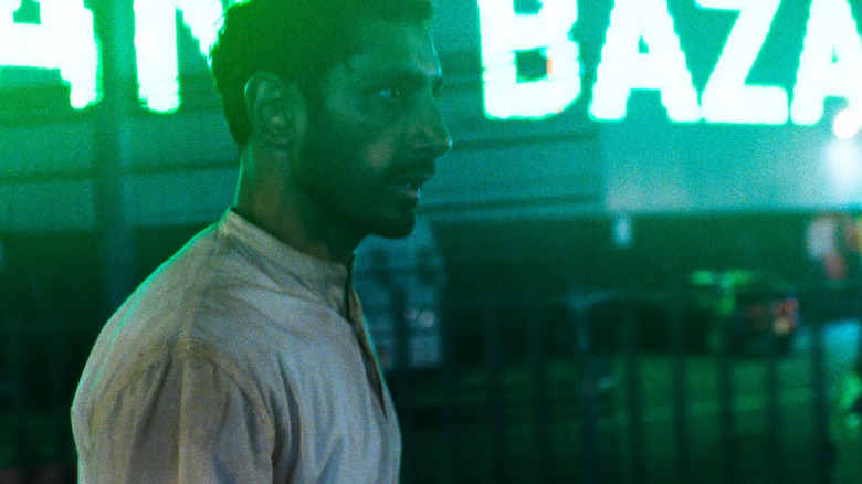 Hamlet walks outside at night in green neon light in "Hamlet" (2025)