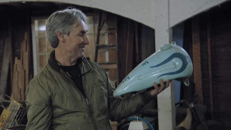 Mike Wolfe smiling at pieces of a motorcycle