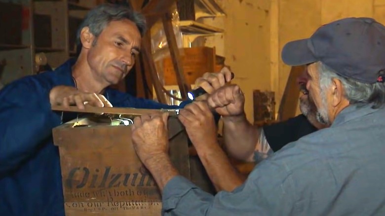 Mike Wolfe and Frank Fritz open a wooden crate