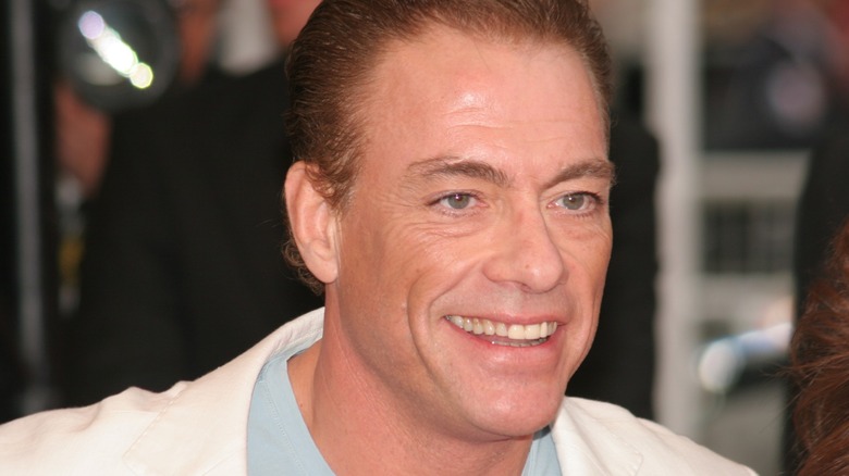 Jean-Claude Van Damme smiling in a white suit