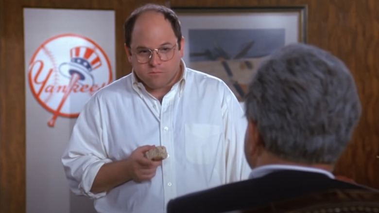 George Costanza standing in front of Yankees logo