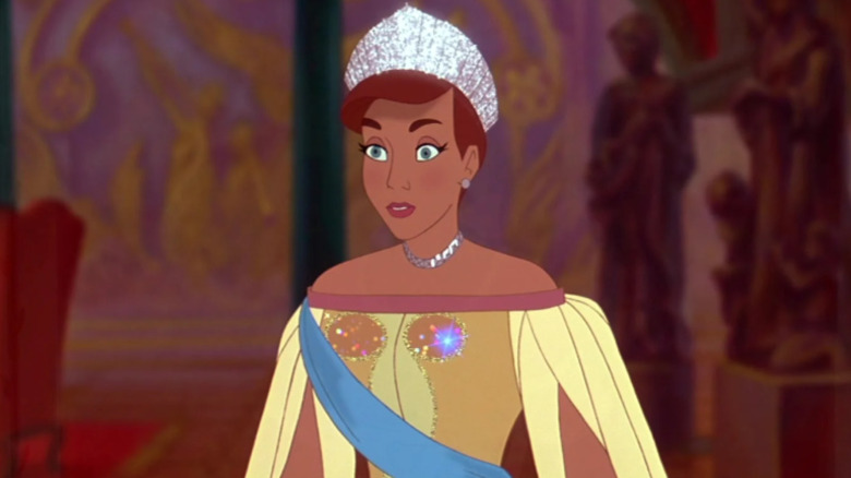 Anastasia standing in a diamond crown and yellow gown with a blue sash
